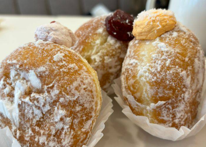 Three cream-filled donuts, filled with custard, pumpkin cream and jam.